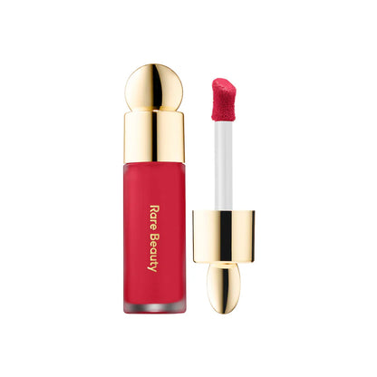 Red lip gloss with gold cap and applicator on a white background, featuring the brand 'Rare Beauty'.